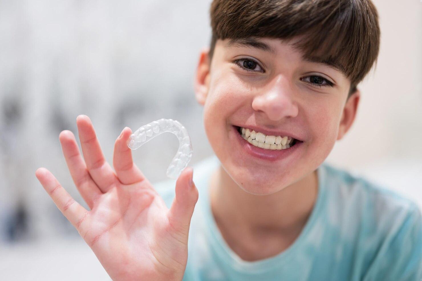 Teen Holding Clear Aligners